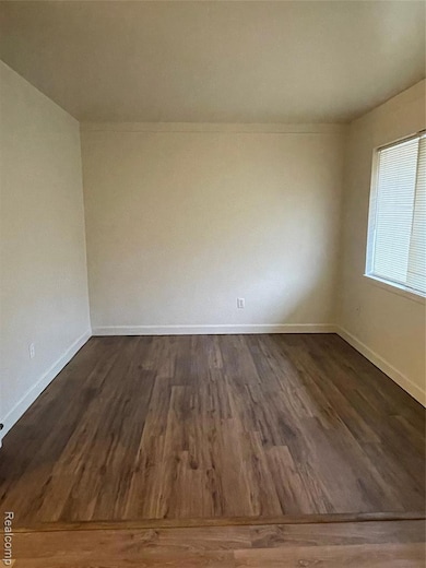 Empty room featuring dark wood-type flooring and baseboards