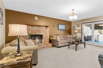 Carpeted living room with a chandelier, a fireplace, and french doors