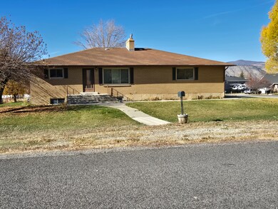 Ranch-style home featuring brick siding, a front yard, a mountain view, and a chimney