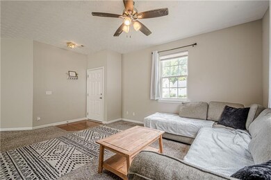 Carpeted living room with ceiling fan, baseboards,