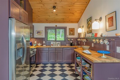 Kitchen with butcher block countertops, wood ceiling, stainless steel appliances, vaulted ceiling, and wainscoting
