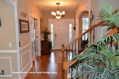 Inviting Entry foyer with hardwood flooring, cased opening going into the connected rooms, wainscoting, side lights on each side of the entry door, and upgraded metal balusters and oak handrails on the open section of the stair case.