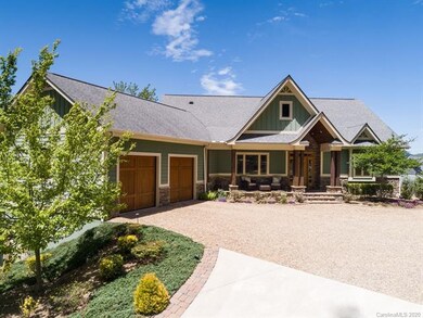 Concrete upper drive is flanked by pavers and stone.  The entrance to the lower level garage/workshop is hidden by the tree.