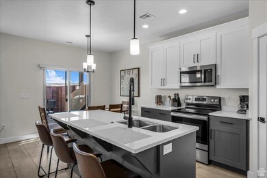 Kitchen with appliances with stainless steel finishes, hanging light fixtures, white cabinetry, light stone countertops, and recessed lighting