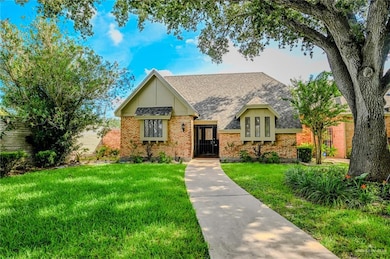 View of front facade with a front yard, a shingled roof, and brick siding