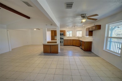 Kitchen featuring a ceiling fan, open floor plan, brown cabinets, and decorative backsplash