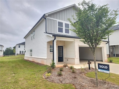 View of front of house with a front lawn, board and batten siding, brick siding, driveway, and a porch