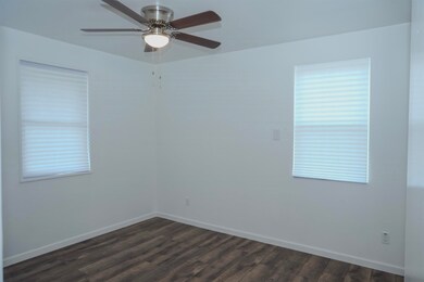 Empty room with dark wood-type flooring, a ceiling fan, and plenty of natural light