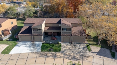 View of front facade featuring a balcony, driveway, brick siding, and roof with shingles