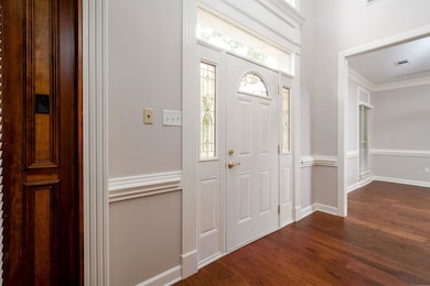 Foyer with dark wood-style floors, baseboards, and ornamental molding