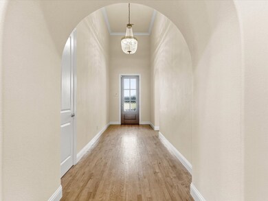 Entryway with wood finished floors, ornamental molding, a chandelier, and a high ceiling