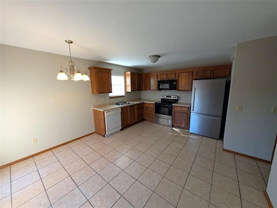 Kitchen with white appliances, light countertops, light tile patterned floors, decorative light fixtures, and a chandelier
