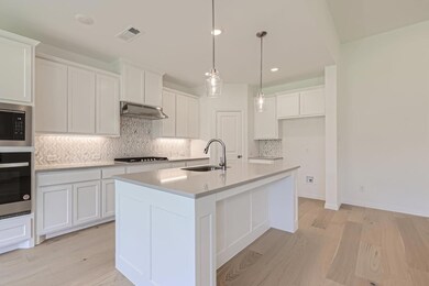 Kitchen featuring wall chimney range hood, white cabinets, backsplash, appliances with stainless steel finishes, and sink