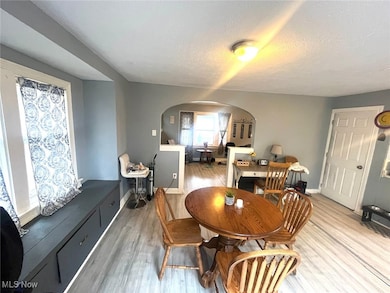 Dining area with arched walkways, wood finished floors, and a textured ceiling