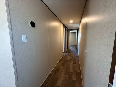 Hallway with a textured wall and dark wood-style floors