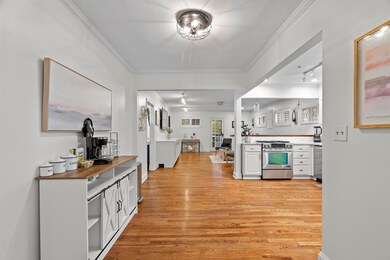 Kitchen featuring crown molding, light wood finished floors, gas stove, white cabinetry, and open floor plan