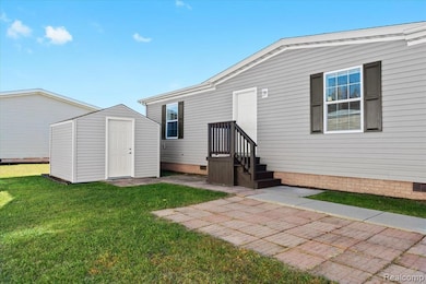 Rear view of property with crawl space, a storage shed, and a lawn