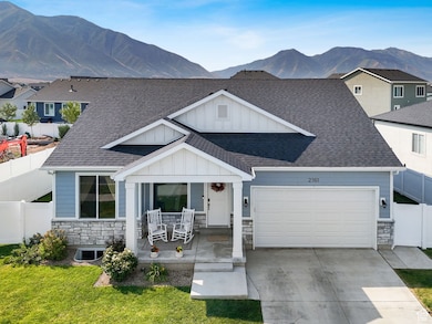 View of front of home with stone siding, covered porch, board and batten siding, and roof with shingles