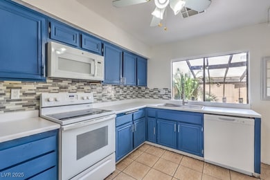 Kitchen with white appliances, blue cabinets, and
