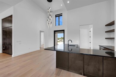 Kitchen featuring open shelves, a sink, dark coun