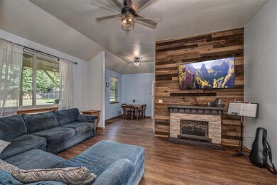 Living area featuring a ceiling fan, wood-style flooring, and a wood paneled wall