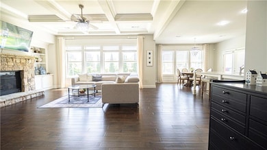 Living room featuring baseboards, dark wood-style flooring, a ceiling fan, a fireplace, and beam ceiling