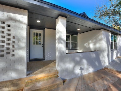 View of exterior entry featuring a porch and brick siding