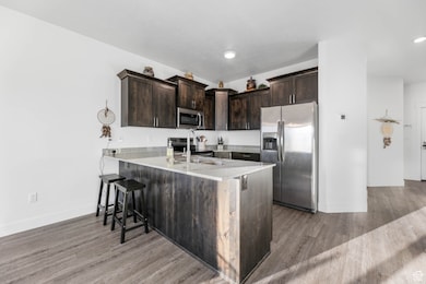 Kitchen featuring stainless steel appliances, open floor plan, staggered knotty alder cabinets, granite countertops, and laminate floors.