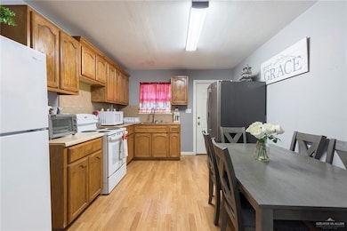 Kitchen with white appliances, decorative backsplash, light hardwood / wood-style flooring, and sink