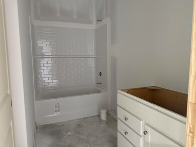 Full bathroom featuring unfinished concrete floors, vanity, and shower / bathtub combination