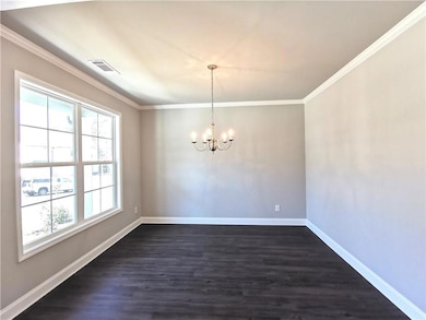 Empty room with dark wood finished floors, a chandelier, and ornamental molding