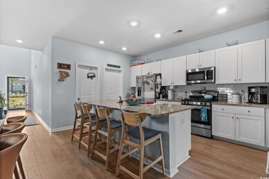 Kitchen featuring stainless steel appliances, a kitchen island with sink, light wood-style floors, a breakfast bar, and recessed lighting