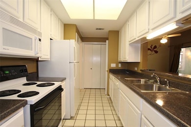 Kitchen with white appliances, a sink, white cabi