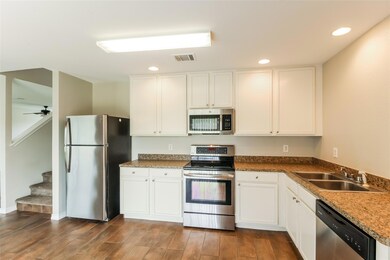 Kitchen featuring appliances with stainless steel finishes, ceiling fan, hardwood / wood-style flooring, white cabinetry, and sink