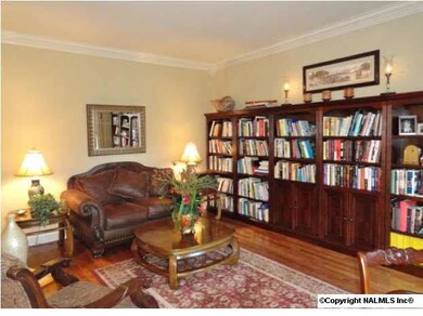 Library with crown moulding, built-ins and wood flooring