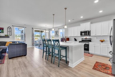 Kitchen with a sink, open floor plan, appliances with stainless steel finishes, decorative backsplash, and a chandelier