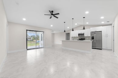 Kitchen featuring stainless steel appliances, pendant lighting, decorative backsplash, open floor plan, and a kitchen island with sink