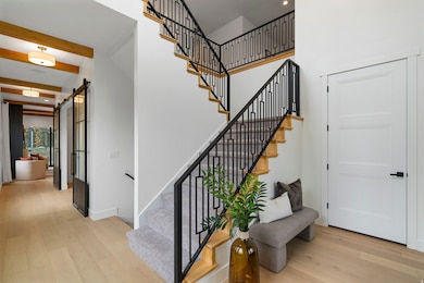 Stairs featuring wood finished floors, a barn door, beamed ceiling, a high ceiling, and recessed lighting