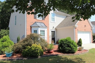 View of front facade with roof with shingles, brick siding, an attached garage, and driveway