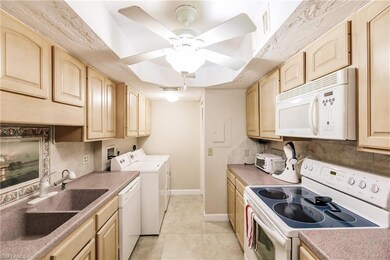 Kitchen with washer and dryer, light brown cabinetry, tasteful backsplash, light tile patterned floors, and white appliances