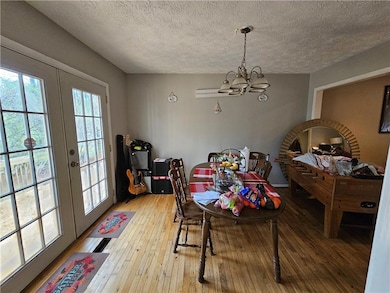 Dining area featuring french doors, a chandelier, light wood-type flooring, and a textured ceiling