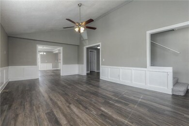 Spare room with ceiling fan, a decorative wall, dark wood-style floors, a chandelier, and wainscoting