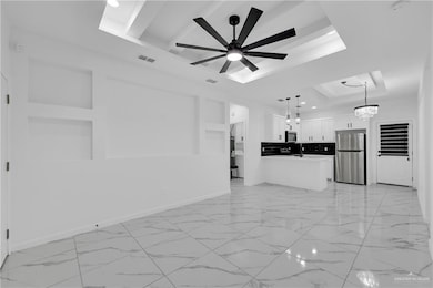 Unfurnished living room with a tray ceiling and ceiling fan with notable chandelier