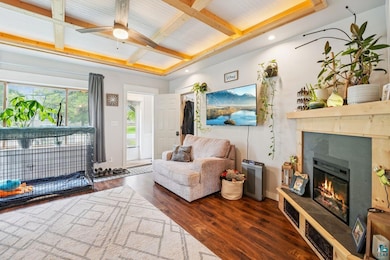 Living area featuring a premium fireplace, wood finished floors, beam ceiling, a ceiling fan, and coffered ceiling