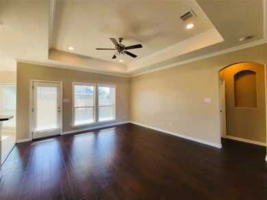 Unfurnished room with arched walkways, a tray ceiling, dark wood finished floors, crown molding, and recessed lighting