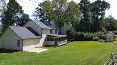 View of green lawn with a sunroom and a shed