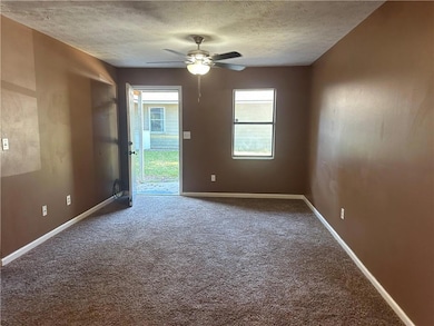 Empty room featuring carpet flooring, a textured ceiling, and ceiling fan