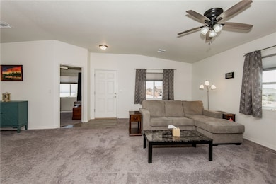 Carpeted living room with ceiling fan, vaulted cei