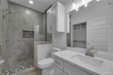 Bathroom featuring vanity, tiled shower, and toilet