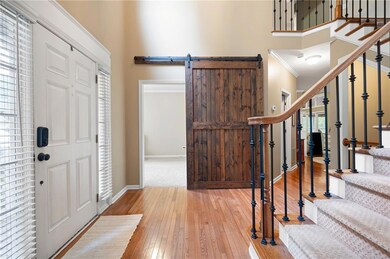 Two-story foyer with sliding barn door leading to main level bedroom/office